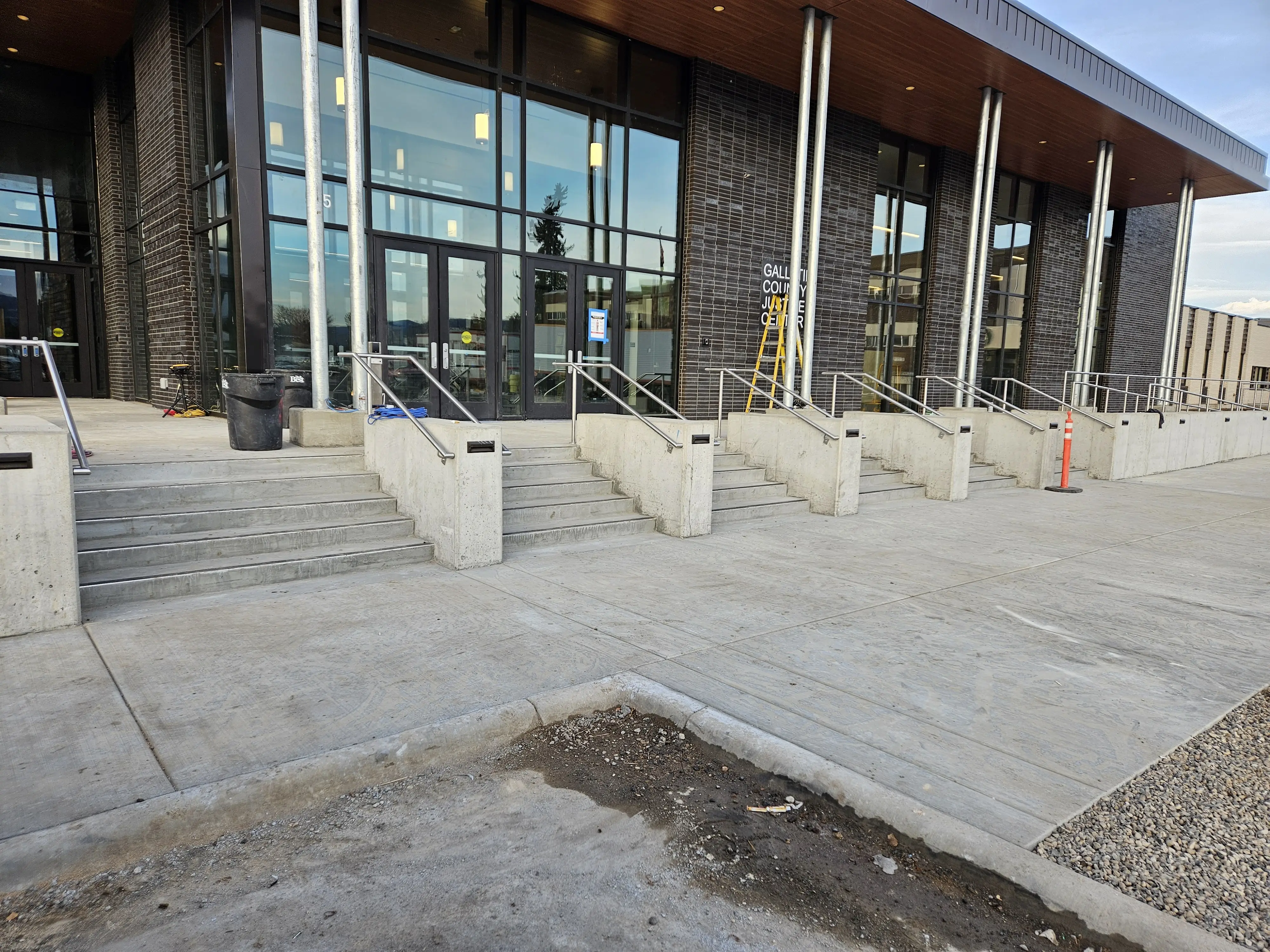 A commercial storefront entrance with concrete steps and stainless steel handrails