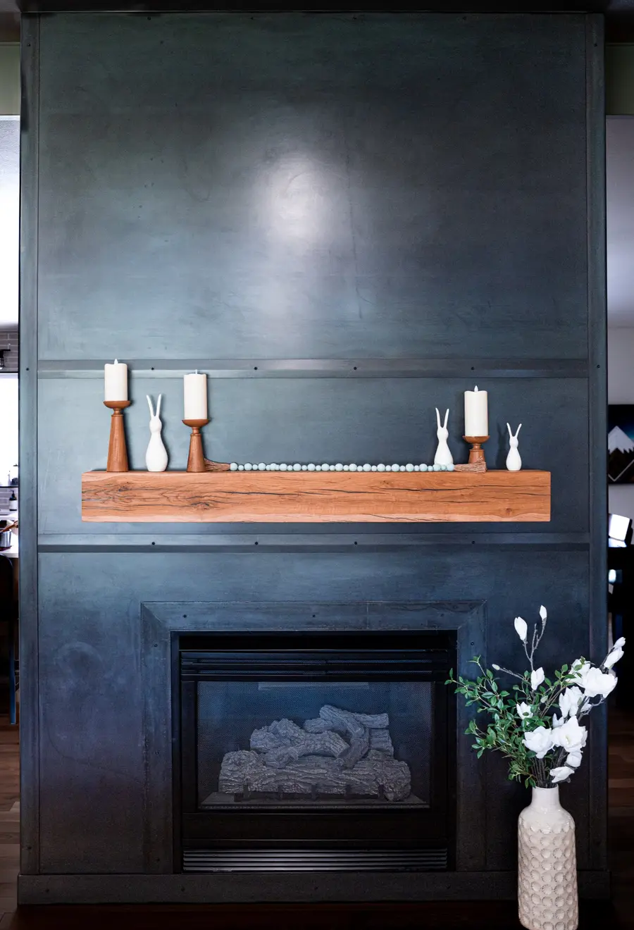 A blackened-steel fireplace surround with a live-edge wood mantel