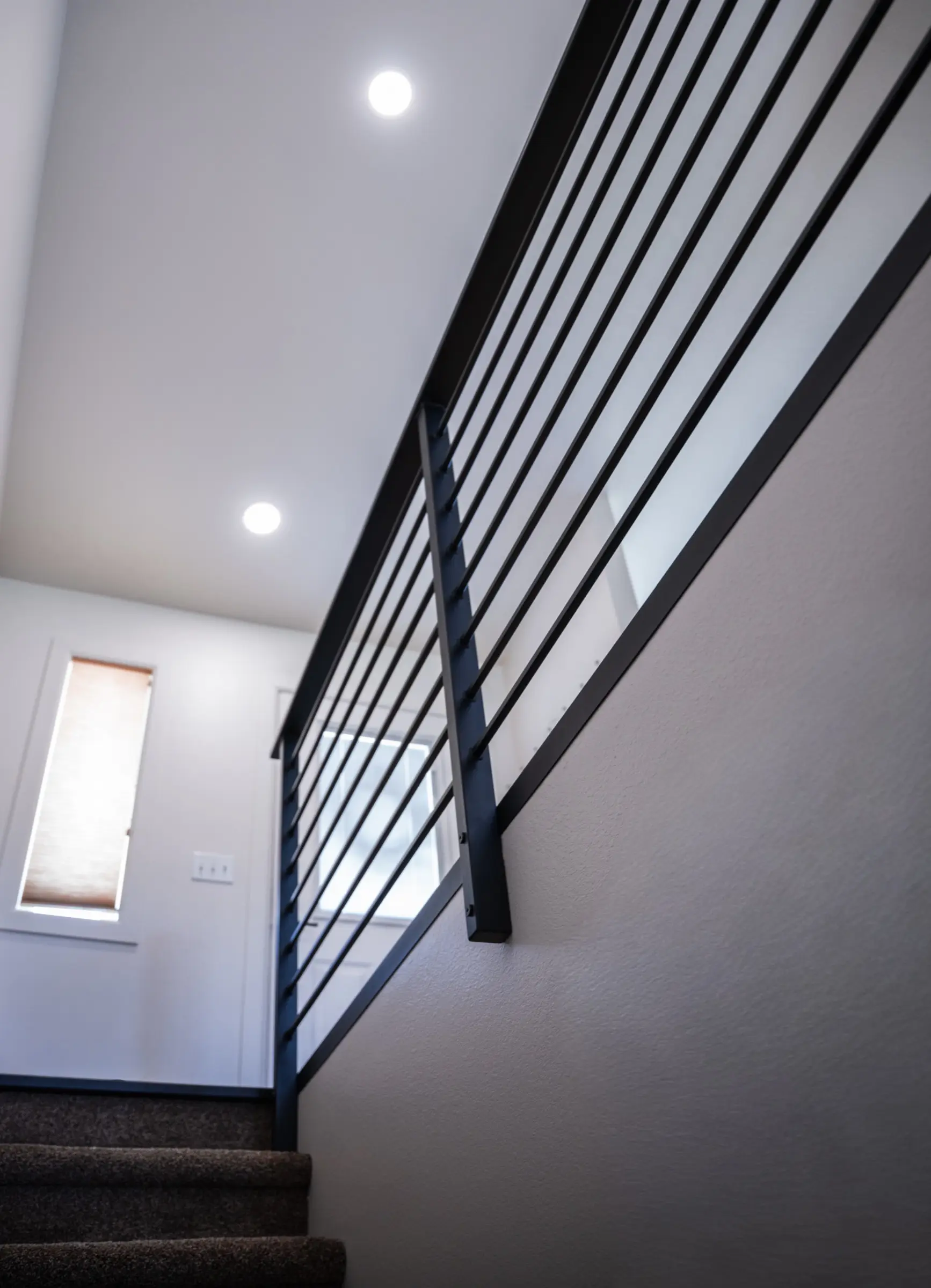 A modern black steel railing running up an open stairwell