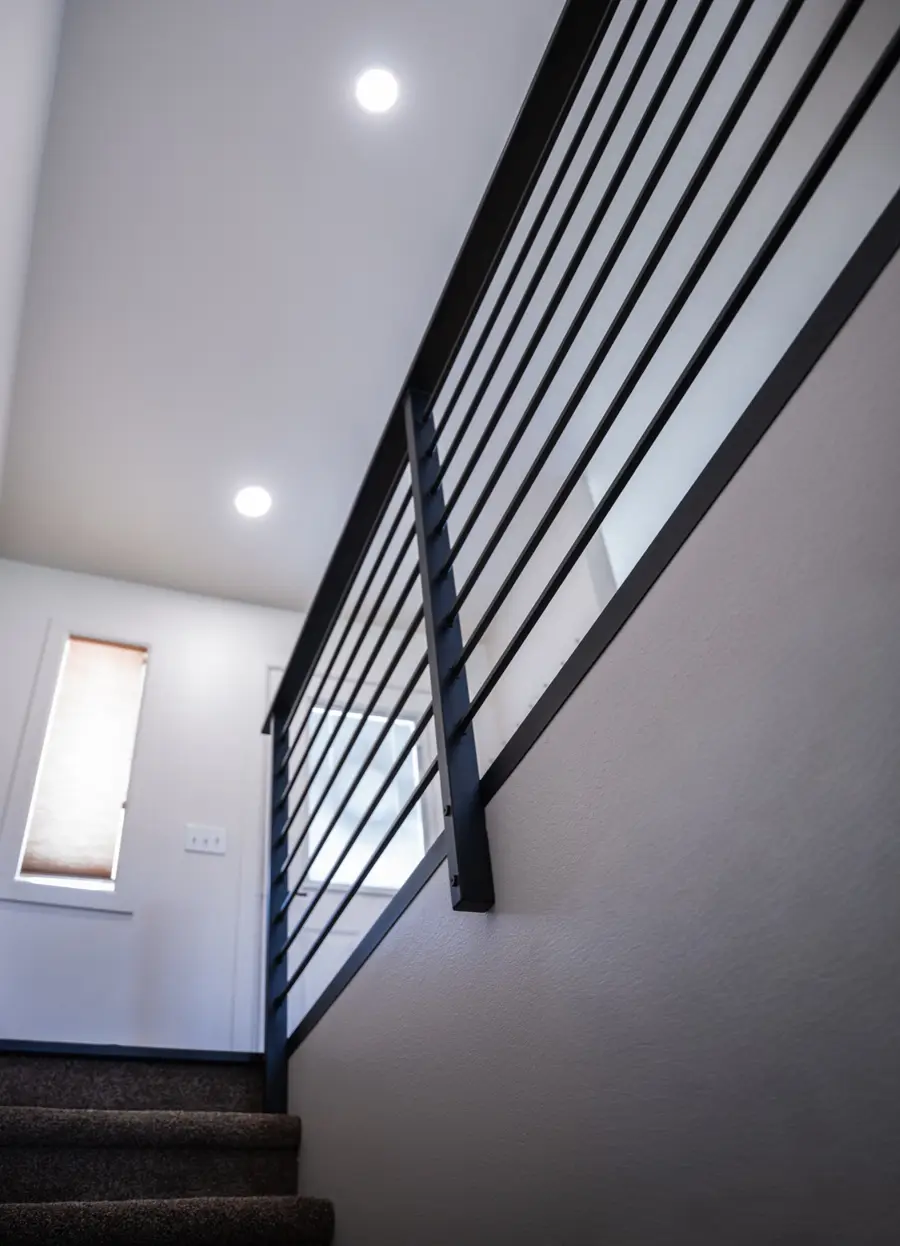 A modern black steel railing running up an open stairwell