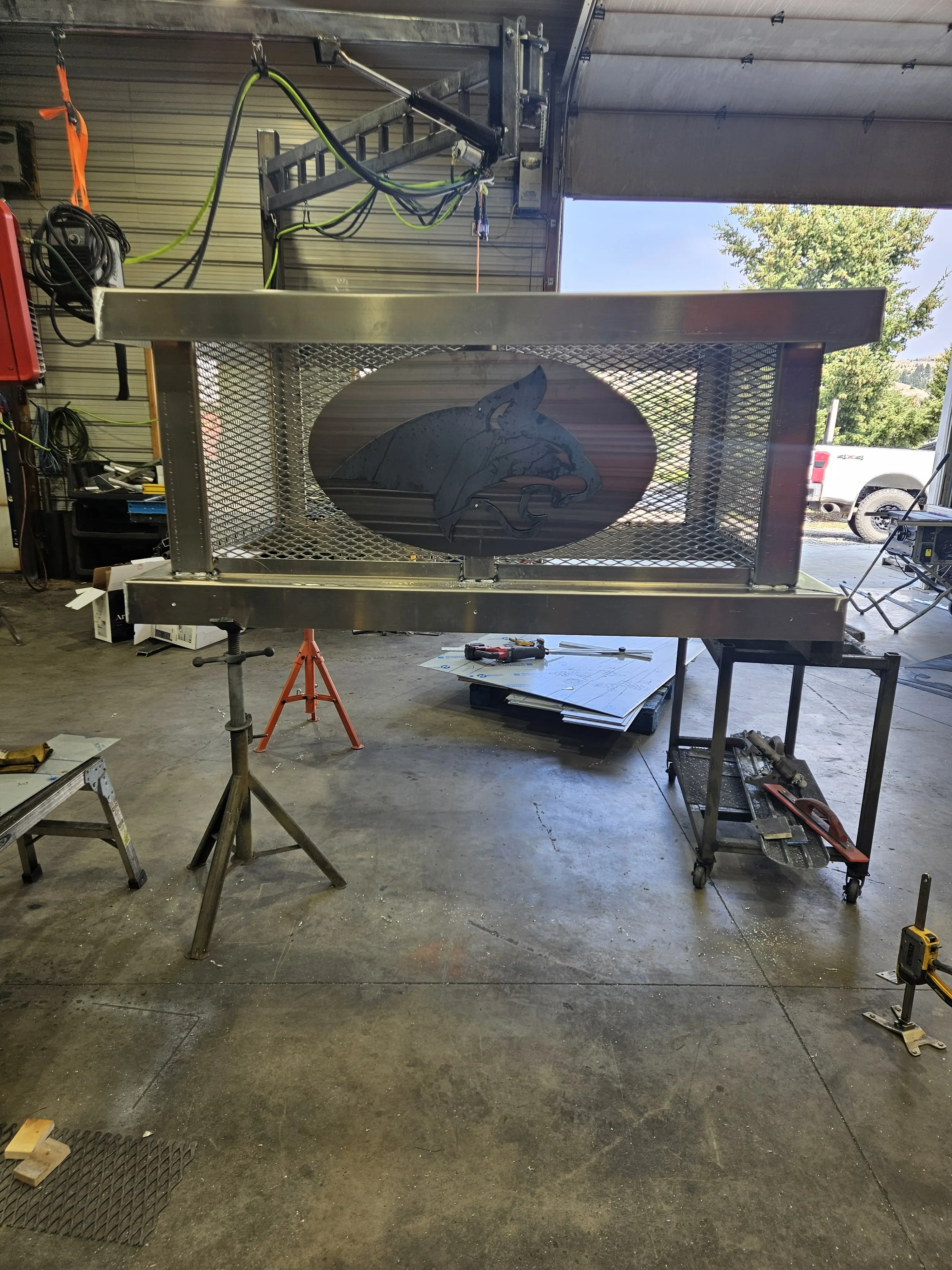 A custom steel smoker with a plasma-cut wolf design in the shop