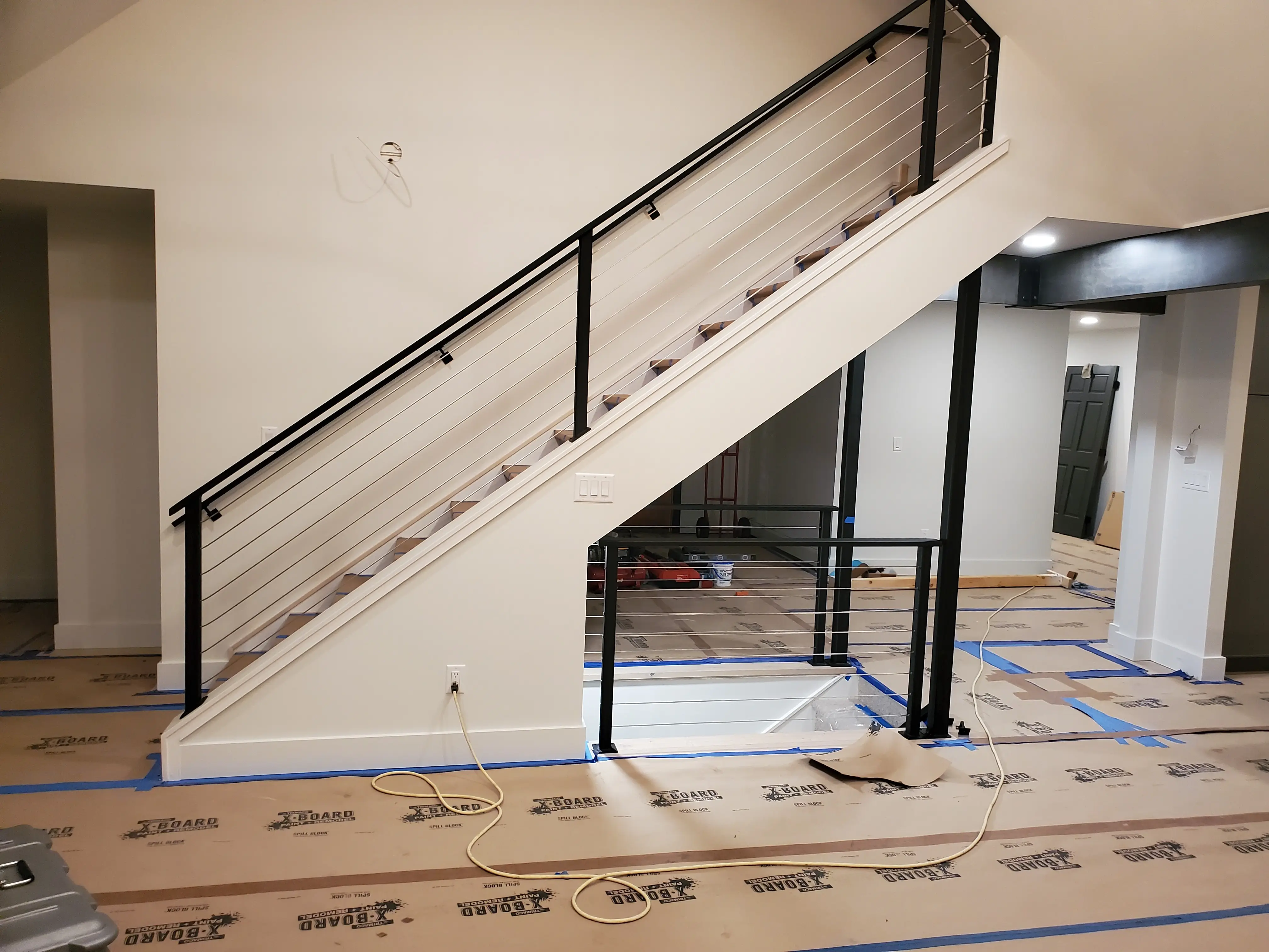An interior staircase with a horizontal cable-style steel railing